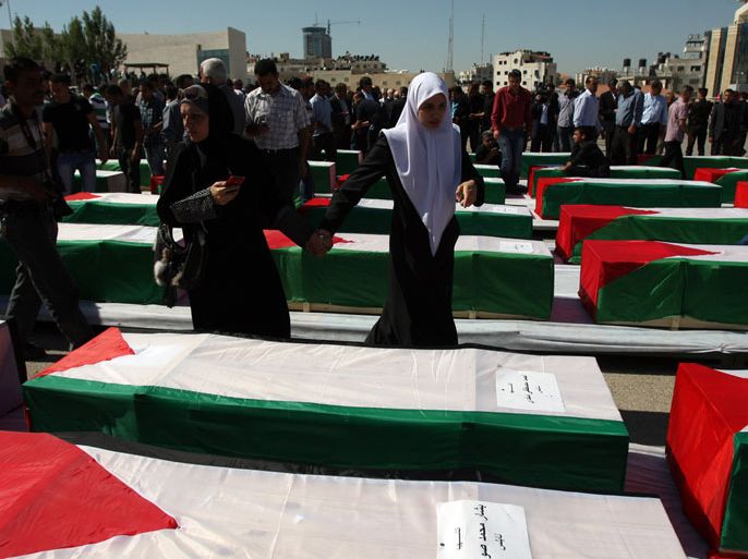 Palestinian women search through flag-draped coffins for their loved ones prior to the funeral of 91 Palestinians whose remains were returned by Israel at the Palestinian leadership headquarters in the West Bank city of Ramallah on May 31, 2012. Israel handed over the remains of scores of Palestinian militants killed in attacks against Israel, a Palestinian official said. AFP PHOTO/ABBAS MOMANI