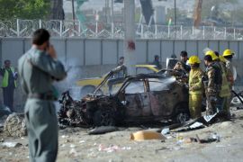 Afghan firefighters distinguish a burning vehicle in front of a guesthouse in Kabul on May 2, 2012,