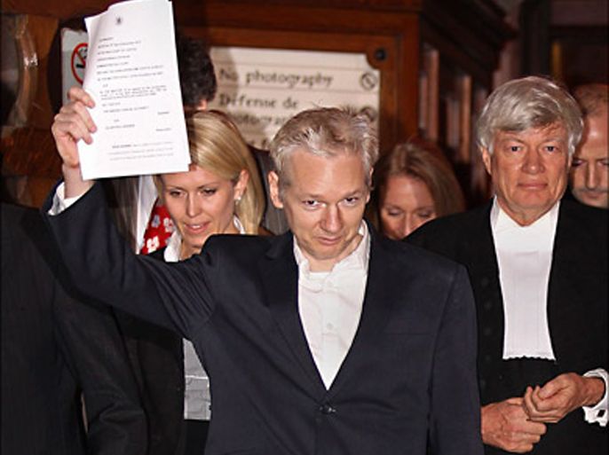r_wikileaks founder julian assange holds up court documents as he emerges to speak to the media on the steps of the high court, in london december 16, 2010 (رويترز)