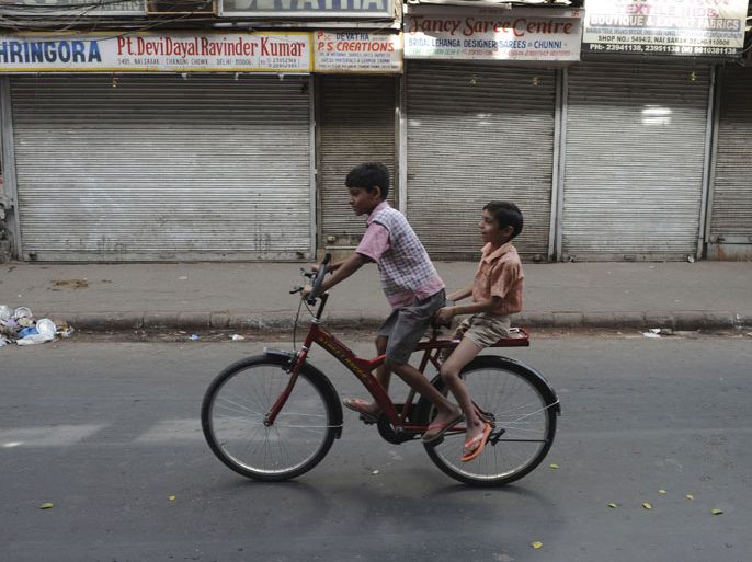INDIA : Indian children ride a bicycle in front of shuttered shops during a nationwide strike in the old quarters of New Delhi on May 31, 2012. India's opposition parties held a nationwide strike May 31, vowing to shut down the country to protest against petrol price rises announced last week. AFP PHOTO/ SAJJAD HUSSAIN