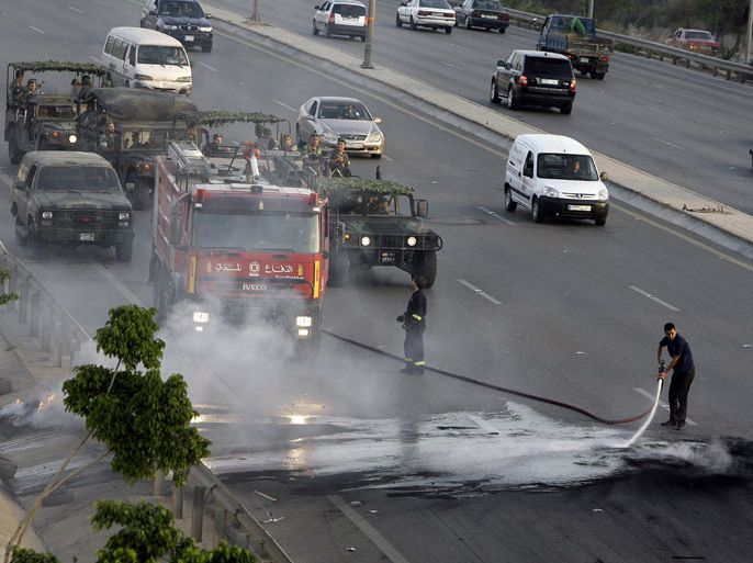 Lebanese civil defence personnel clean the road from burning tires after Muslim Shiite men blocked the highway leading to Beirut airport on May 23, 2012 to
