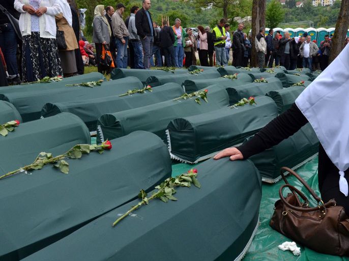 A Bosnian Muslim woman cries near the casket containing her relative's remains among 66 caskets during a mass burial ceremony in the Eastern Bosnian town of Visegrad, on May 26, 2012.
