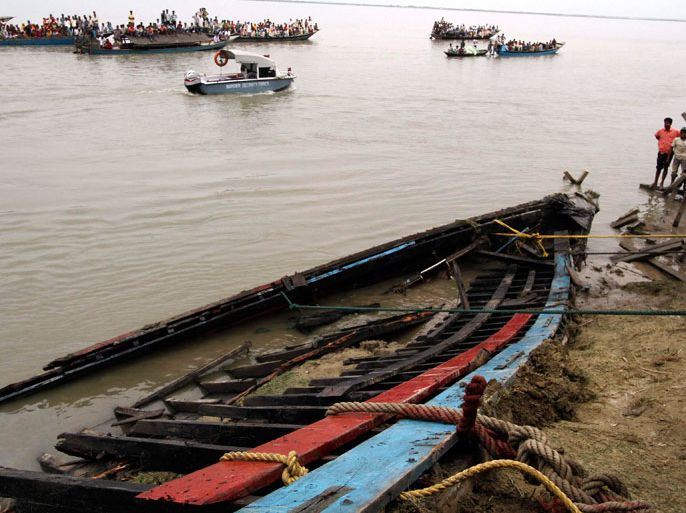 Onlookers and rescue workers look at the damaged boat which was taken on shore after it sank on the Brahmaputra river, at Buraburi village in Dhubri district of the northeastern Indian state of Assam May 1, 2012. Rescue workers fought heavy wind and rain to search for survivors after at least 103 people drowned on an overloaded ferry carrying about 300 people that sank at night on one of India's largest rivers on Monday, police said. REUTERS/Utpal Baruah (INDIA - Tags: DISASTER TRANSPORT)