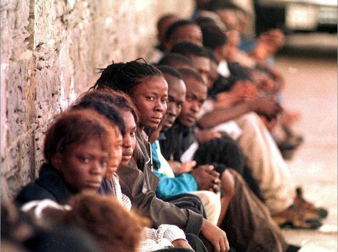 ALG02 - 20000824 - ALGECIRAS, CADIZ, SPAIN : A group of illegal immigrants sits leaning against a wall as they wait to be moved out of the country at the port of Algeciras (southern Spanish Cadiz region) after being detained in Tarifa on Thursday, 24 August 2000. Police detained a total of 185 people trying to enter Spain illegally by sea on Thursday bringing the number of African nationals caught over the last week to nearly 600. Spanish authorities arrested the illegal immigrants from Africa in five separate swoops in southern Spain and the straits of Gibraltar, the civil guard said. EPA PHOTO EFE/J.RAGEL/aa/kr