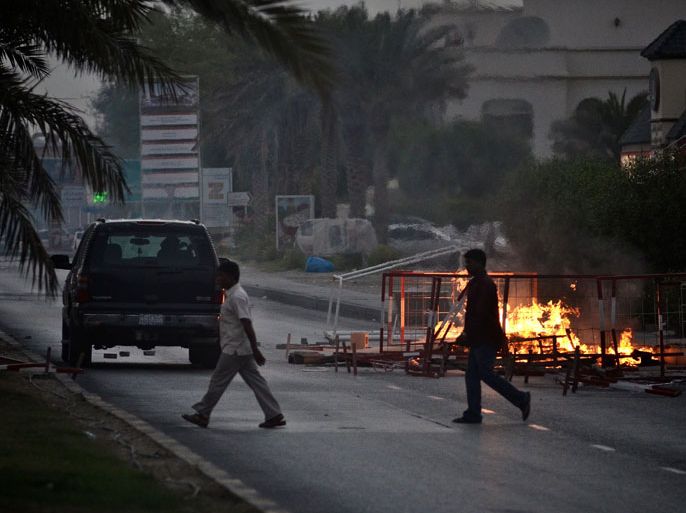 BAHRAIN : Bahraini men walk past a burning barricade during an anti-government demonstration in the village of Abu Saiba, west of Manama on June 8, 2012. Bahrain came under strong criticism from international rights organisations over last year's crackdown on demonstrations that were inspired by the Arab Spring uprisings. AFP PHOTO/MOHAMMED AL-SHAIKH
