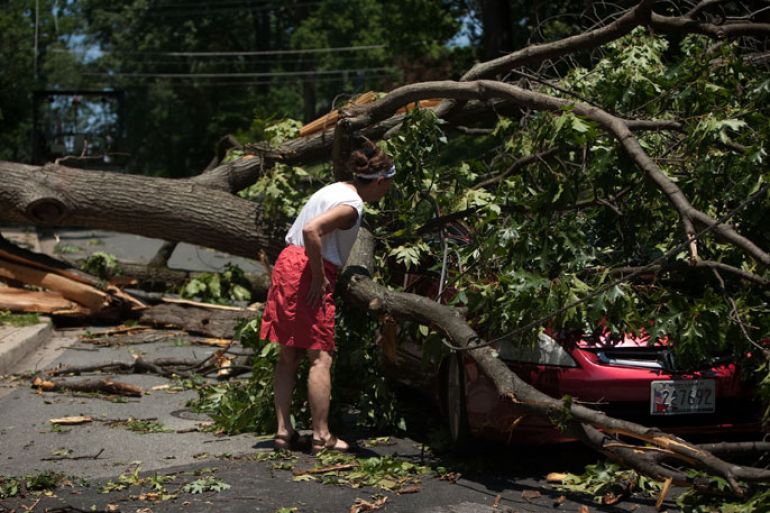 Takoma Park, Maryland, UNITED STATES : TAKOMA PARK, MD - JUNE 30: A woman inspects a car left in the middle of the road after a massive storm knocked out power on June 30, 2012 Takoma Park, Maryland. The severe storm has left more than a million people in the Maryland, Northern Virginia and the District area without power and at least five dead. Allison Shelley/Getty Images/AFP== FOR NEWSPAPERS