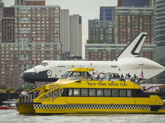 Riders onboard a New York Water Taxi get a close-up view of the US space shuttle Enterprise as it is towed by barge up the Hudson River on it's way to the Intrepid Sea, Air and Space Museum where it will be permanently displayed, Wednesday, June 6, 2012 in New York City. AFP