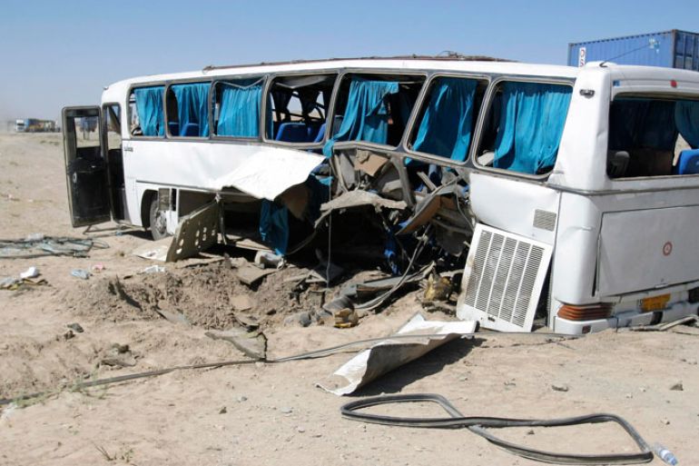 The wreckage of a bus that was damaged in a roadside bomb blast sits beside a road in Ghazni, July 1, 2012