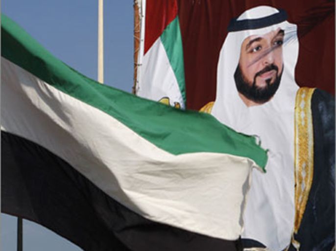 a united arab emirates flag waves in front of a big poster of president sheikh khalifa bin zayed al-nahayan in abu dhabi december 15,2009. abu dhabi threw its flashy (رويترز)