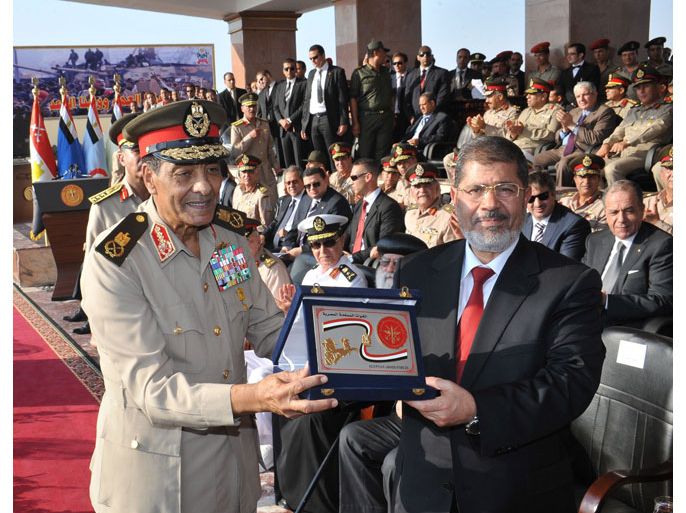Cairo, -, EGYPT : In this handout picture made available by the Egyptian presidency on June 30, 2012, (L to R) military council chief Field Marshal Hussein Tantawi (L), presents the "shield of the Armed Forces" the Egyptian military's highest honor to President Mohamed Morsi (R) during a ceremony at a military base in of Cairo. Morsi was sworn in as Egypt's first freely elected civilian president on Saturday and formally received