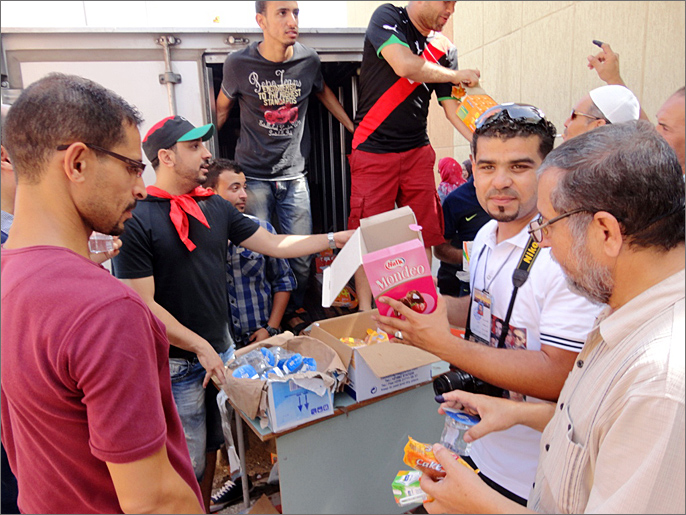 ‪شباب يوزعون الحلوى والعصائر على مرتادي المراكز الانتخابية‬ (الجزيرة)