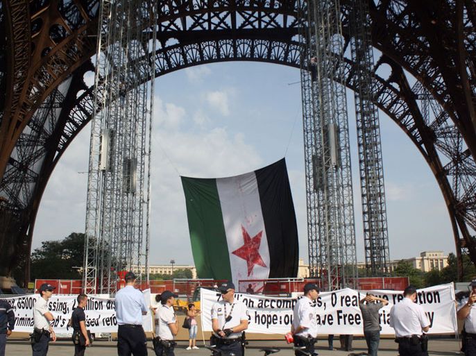 Paris, Paris, FRANCE : Policemen stand in front of a giant Syrian revolutionary flag, hung by two militants in support to the Syrian uprising, after they climbed the scaffolding placed under the Eiffel Tower, on July 27, 2012 in Paris.