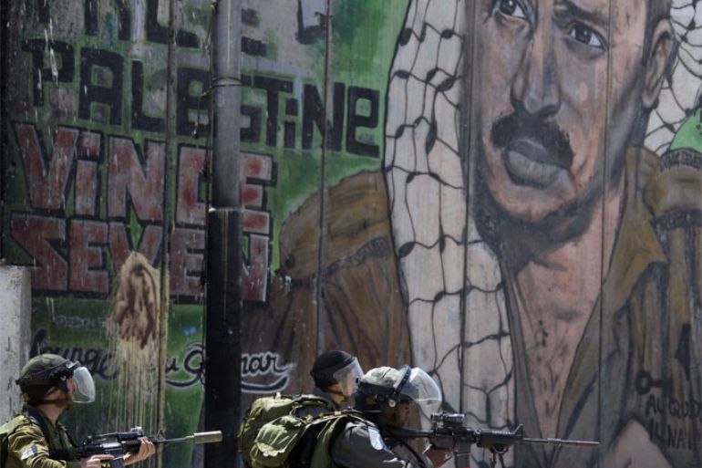 Israeli soldiers take position next to a mural painting of late Palestinian leader Yasser Arafat on Israel's separation barrier at the Qalandia crossing in the occupied West Bank during protests on May 15, 2012, marking Nakba day, which commemorates the exodus of hundreds of thousands of their kin after the establishment of Israel state in 1948.