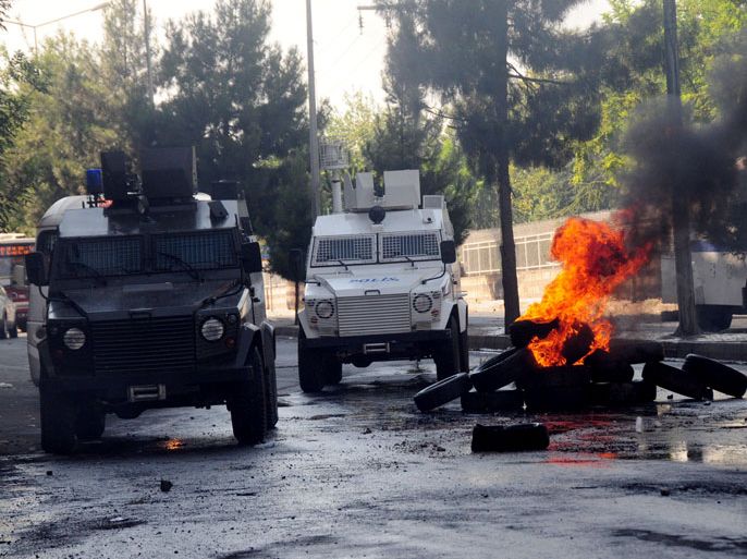 Smoke rises from burning tires next to a police vehicle as Kurdish demonstrators clash with Turkish police during a rally outlawed by state authoritites to demand the release of jailed rebel leader Abdullah Ocalan , on July 14, 2012, in Diyarbakir. At least 20 people were wounded in the clashes. Several hundred