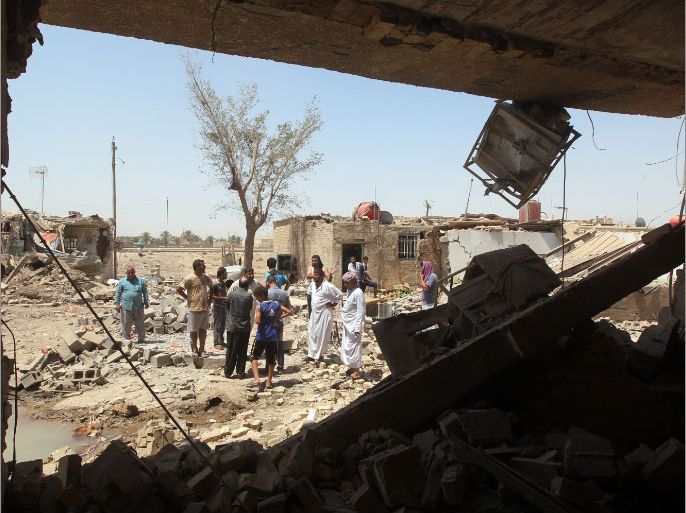 Iraqis stand amidst the rubble of destroyed houses following a series of bomb attacks in the town of Taji, north of Baghdad which killed at least 42 people and wounded 40, on July 23, 2012. A wave of attacks in Baghdad and north of the capital killed 91 people in Iraq's deadliest day in more than two years after Al-Qaeda warned it would mount new attacks and sought to retake territory. AFP PHOTO / AHMAD AL-RUBAYE