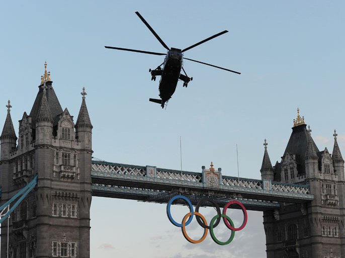 A Sea King helicopter carrying the Olympic Flame flies over London's Tower Bridge on July 20, 2012, as British Royal Marine Commando Martyn Williams prepares to abseil from the helicopter with the Olympic Flame down to the Tower of London. The Olympic flame made a dramatic arrival in London on Friday to tour the capital