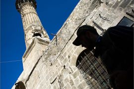 A Syrian rebel fighter is pictured in front of the Mamluk-era Mohamandar mosque in the Bab an-Nasr district of Aleppo's Old City on August 20, 2012. The minaret of the mosque was hit by a rocket-propelled grenade, which according to the opposition forces was fired by Syrian government troops. AFP PHOTO/PHIL MOORE