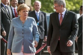 German Chancellor Angela Merkel (R) greets Canadian Prime Minister Stephen Harper walk towards the Canadian Parliament August 16, 2012 in Ottawa, Ontario. German leader Merkel will hold trade talks with her Canadian counterpart on a first-ever bilateral visit. AFP PHOTO / ROGERIO BARBOSA