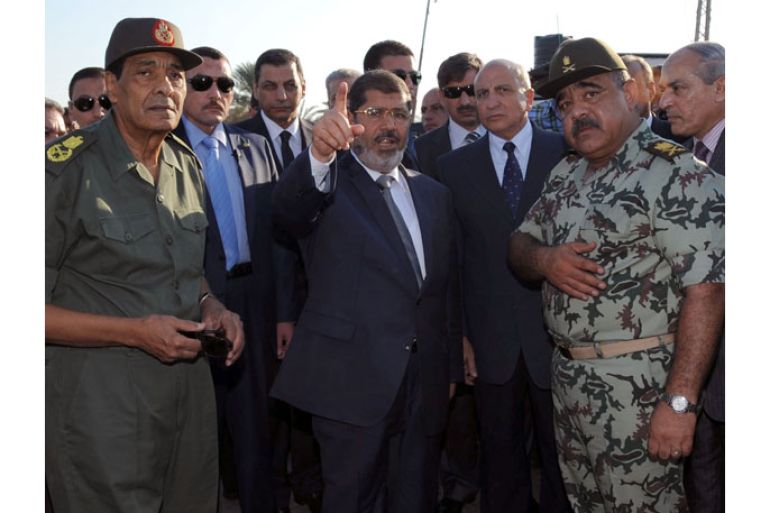 A handout photo released by the Egyptian Presidency shows Egyptian President Mohamed Morsi (C) and Minister of Defence Field Marshal Mohammed Hussein Tantawi (L) inspecting a security checkpoint in Arish, northern Sinai, Egypt, 06 August 2012. Media reports state that 16 Egyptian security forces were killed and seven others injured on 05 August when militants opened fire on a checkpoint and commandeered vehicles during a Ramadan fast in Rafah. Having hijacked the vehicles, they raced to the nearby Kerem Shalom/Karm Abu Salem crossing point on the Egypt-Israel-Gaza border. Egyptian authorities closed the border crossing with the Gaza Strip at Rafah indefinitely. EPA/EGYPTIAN PRESIDENCY/HANDOUT HANDOUT EDITORIAL USE ONLY/NO SALES
