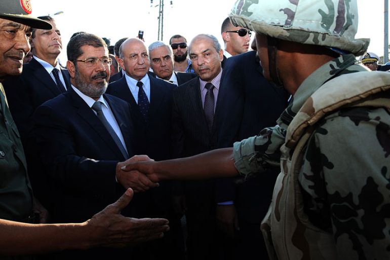 This hand out picture made available by the Egyptian presidency on August 6, 2012, shows Egyptian President Mohamed Morsi (C) and Egyptian Defence Minister and Field Marshall Hussein Tantawi (L) as they visit soldiers in al-Arish, in the northern Sinai. Egypt's army vowed to "avenge" the killing of 16 troops by gunmen near the Israeli border, as President Mohamed Morsi ordered security forces to take full control of the Sinai Peninsula. In yesterday's attack, 35 gunmen in Bedouin clothing opened fire on the troops before crossing into the Jewish state in an armoured vehicle, Egyptian officials said. Israel said five gunmen were killed on its side. AFP PHOTO/EGYPTIAN PRESIDENCY == RESTRICTED TO EDITORIAL USE - MANDATORY CREDIT "AFP PHOTO/EGYPTIAN PRESIDENCY" - NO MARKETING NO ADVERTISING CAMPAIGNS - DISTRIBUTED AS A SERVICE TO CLIENTS ==