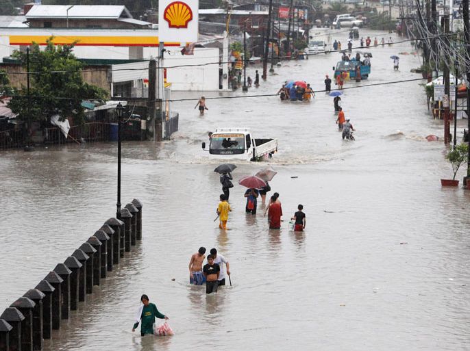 Residents wade on a flooded street in Las Pinas, Metro Manila August 7, 2012. Monsoon rains swamped the Philippine capital and nearby provinces, forcing the government to close schools, public and private offices and financial markets, as emergency workers rushed to move thousands of people to higher grounds, government disaster officials said. REUTERS/Erik De Castro (PHILIPPINES - Tags: ENVIRONMENT DISASTER SOCIETY)