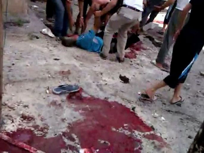 An image grab taken from a video uploaded on YouTube on July 27, 2012, shows Syrians lifting the body of a man who was allegedly killed during regime force shelling on Syria's northern restive city of Aleppo