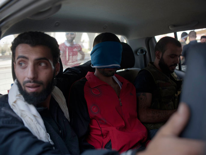 مقاتلون من الجيش الحر ينقلون داخل سيارة مواليا للنظام اعتقلوه في حلب (الفرنسية)