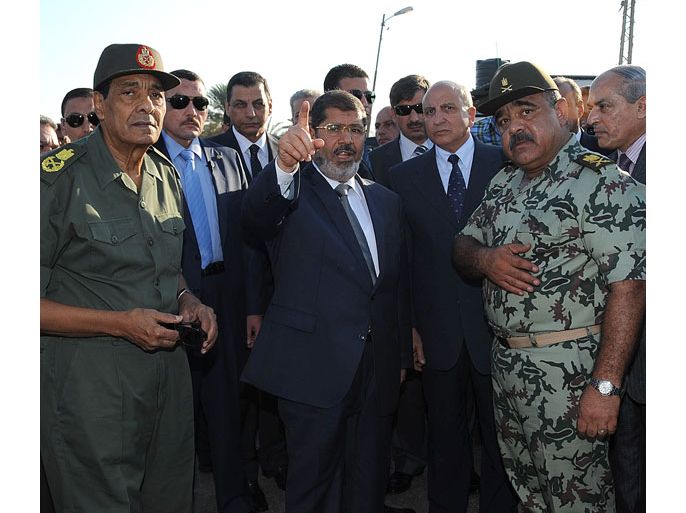 This hand out picture made available by the Egyptian presidency on August 6, 2012, shows Egyptian President Mohamed Morsi (C) and Egyptian Defence Minister and Field Marshall Hussein Tantawi (L) visit a checkpoint and soldiers in al-Arish, in the northern Sinai. Egypt's army vowed to "avenge" the killing of 16 troops by gunmen near the Israeli border, as President Mohamed Morsi ordered security forces to take full control of the Sinai Peninsula. In yesterday's attack, 35 gunmen in Bedouin clothing opened fire on the troops before crossing into the Jewish state in an armoured vehicle, Egyptian officials said. Israel said five gunmen were killed on its side. AFP PHOTO/EGYPTIAN PRESIDENCY == RESTRICTED TO EDITORIAL USE - MANDATORY CREDIT "AFP PHOTO/EGYPTIAN PRESIDENCY" - NO MARKETING NO ADVERTISING CAMPAIGNS - DISTRIBUTED