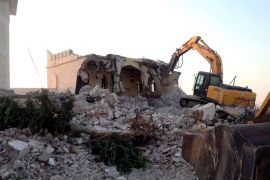 Libyan Islamist hardliners use a bulldozer to raze the mausoleum of Al-Shaab Al-Dahman near the centre of Tripoli on August 25, 2012. Islamist hardliners bulldozed part of the revered mausoleum in Tripoli in the second such attack in Libya in two days, an AFP correspondent reported. AFP PHOTO/MAHMUD TURKIA