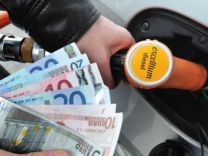 PHU4428 - Lille, Nord, FRANCE : (FILES) - A file picture shows a man filling up at a gas station and holding euros in his hand, on February 28, 2012 in Lille, northern France. The G7 industrial countries called on August 28, 2012 on oil producers to increase output, saying higher prices posed "substantial risks" to the global economy. Under acute political pressure in France to reduce petrol prices at the pump, France's Finance Minister Pierre Moscovici earlier announced the government would spend 300 million euros ($375 million) to temporarily cut pump prices for motorists. AFP PHOTO PHILIPPE HUGUEN
