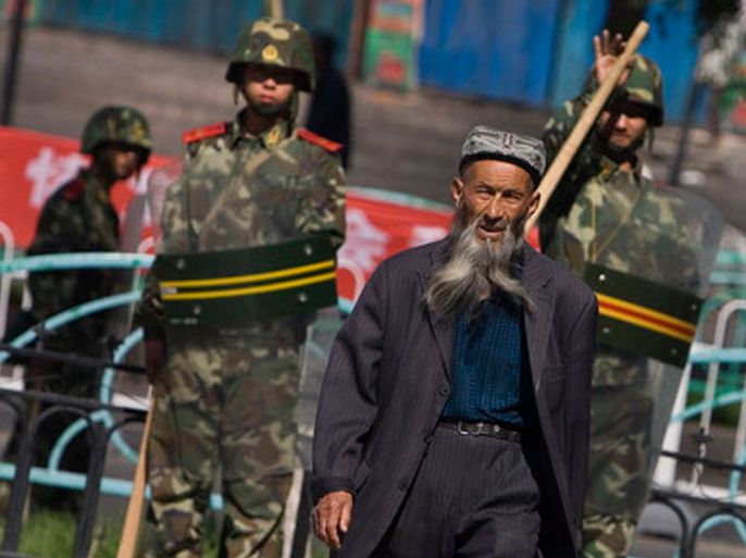 An ethnic Uighur man passes by security forces standing guard outside the Grand Bazaar in Urumqi, Xinjiang province, China, 16 July 2009. The presence of security forces in Urumqi is still very obvious although a number of troops seem to have been left the streets. Tension can still be felt in some areas of the city but businesses are slowly coming back to life, and residents are trying to go back to their routine. EPA/DIEGO AZUBEL