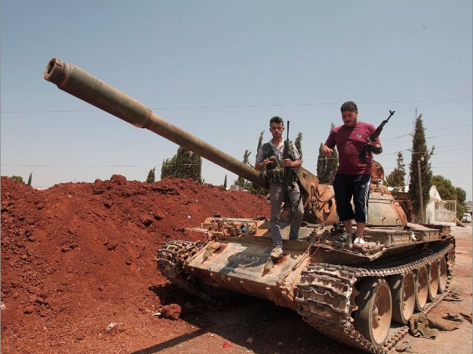 Syrian rebel fighters stand on top of a government tank captured two days earlier at a checkpoint in the village of Anadan, about five kilometres (3.8 miles) northwest of Aleppo, on August 01, 2012. The strategic checkpoint of Anadan secures the rebel fighters free movement between the northern city of Aleppo and Turkey, a Free Syrian Army commander and an AFP journalist said. AFP PHOTO/AHMAD GHARABLI