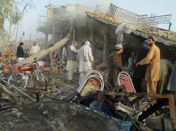 Afghan men stand at the site of a suicide attack in Kandahar on August 28, 2012. A "massive" suicide truck bombing overnight killed four civilians and wounded General Abdul Raziq, the provincial police chief who has a strong anti-Taliban background, authorities said. AFP PHOTO/ JANGIR