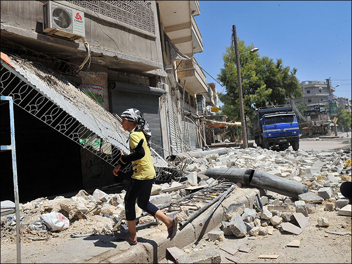 فتاة تسير أمام منزل دمره القصف في حلب (الفرنسية)