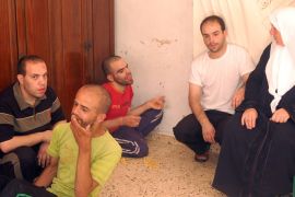 ام حسام تجلس بين ابنائها الاربعة الذين يعانون اعاقات صعبة ومختلفة- الجزيرة نت1
