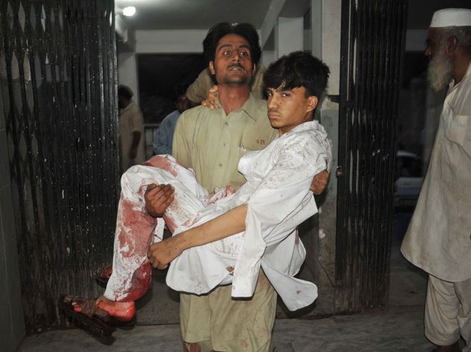 A Pakistani man carries a wounded bomb blast survivor to a hospital in Peshawar