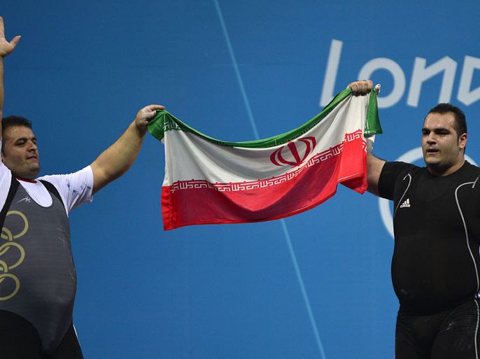 Iran's Behdad Salimikordasiabi (R) celebrates his gold medal next to his teammate Sajjad Anoushiravani Hamlabad (L) who took the silver medal, during the men's +105kg group A weightlifting event of the London 2012 Olympic Games at The Excel Centre in London on August 7, 2012. AFP PHOTO / YURI CORTEZ