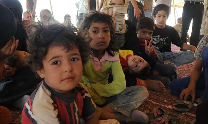 اطفال لاجئون من طفس يجلسون في خيمة لتجميع اللاجئين