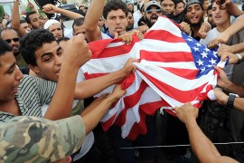 epa03395822 A group of protesters tear up the US flag during a demonstration outside the US Embassy, in Tunis, Tunisia, 12 September 2012. About one hundred people demonstrated in front of the US embassy for the second time in 24 hours on 12 September. Dozens of demonstrators held a sit-in to protest a film that triggered a deadly attack on a US consulate in Libya on 11 September, according to media reports. The demonstrators waved black jihadist flags and carried signs with slogans condemning a US-produced film deemed insulting to the prophet Mohammed, Radio Shems reported. EPA