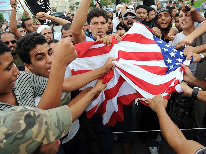 epa03395822 A group of protesters tear up the US flag during a demonstration outside the US Embassy, in Tunis, Tunisia, 12 September 2012. About one hundred people demonstrated in front of the US embassy for the second time in 24 hours on 12 September. Dozens of demonstrators held a sit-in to protest a film that triggered a deadly attack on a US consulate in Libya on 11 September, according to media reports. The demonstrators waved black jihadist flags and carried signs with slogans condemning a US-produced film deemed insulting to the prophet Mohammed, Radio Shems reported. EPA