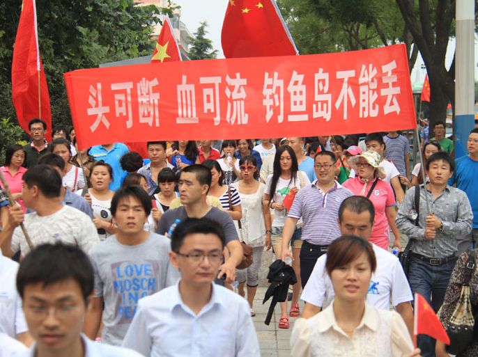 Protesters (behind) hold a banner reading "Heads could be cut off - Blood could be lost - Diaoyu Islands cannot be invaded" as people march down a street in Weihai, in eastern China's Shandong province, to protest against Japan "nationalizing" the Diaoyu islands, also known as the Senkaku Islands in Japanese, on September 11, 2012. China has dispatched two patrol ships to "assert its sovereignty" over islands at the centre of a row with Japan