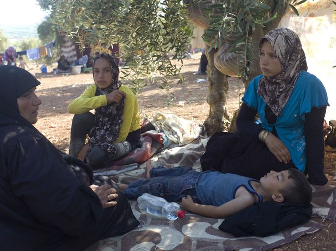 A Syrian refugee family sit outside their makeshift tent in Atme village in the northwestern province of Idlib, bordering Turkey, on September 4, 2012 as hundreds of Syrians flee their villages and camped in the border area.In August 2012, more than 100,000 people fled the war-torn country to seek refuge