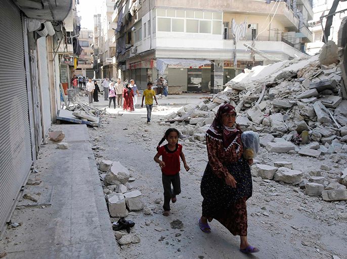 Civilians walk near a destroyed building after a Syrian Air Force fighter jet launched a bomb in the city of Aleppo September 3, 2012. REUTERS