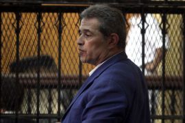 Egyptian talk show host Tawfiq Okasha stands behind bars as he attends his trial on charge of calling for the murder of President Mohamed Morsi, on September 1, 2012 in Cairo. AFP PHOTO/ AHMED MAHMUD