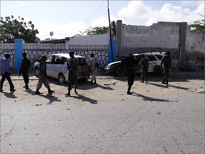 جنود حكوميون أمام سيارات تضررت بالهجوم قرب الفندق (الجزيرة نت)
