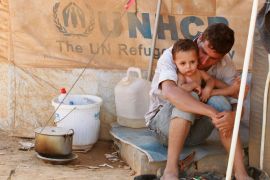 A Syrian refugee holds his child as he sits by his tent at Al Zaatri refugee camp in the Jordanian city of Mafraq, near the border with Syria September 9, 2012. REUTERS/Muhammad Hamed (JORDAN - Tags: CONFLICT)