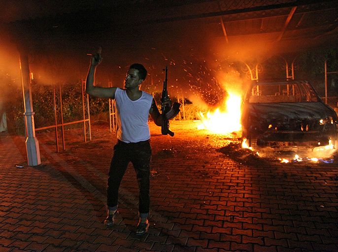 An armed man waves his rifle as buildings and cars are engulfed in flames after being set on fire inside the US consulate compound in Benghazi late on September 11, 2012. An armed mob protesting over a film they said offended Islam, attacked the US consulate in Benghazi and set fire to the building, killing one American, witnesses and officials said. AFP