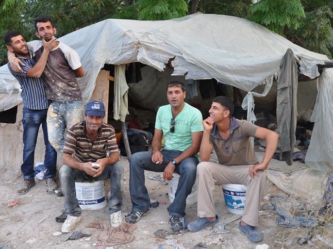 عمال من الضفة الغربية بعد انتهاء يوم العمل يجلسون قبالة خيمة اللجوء المنصوبة بسهول إحدى بلدات الداخل الفلسطيني