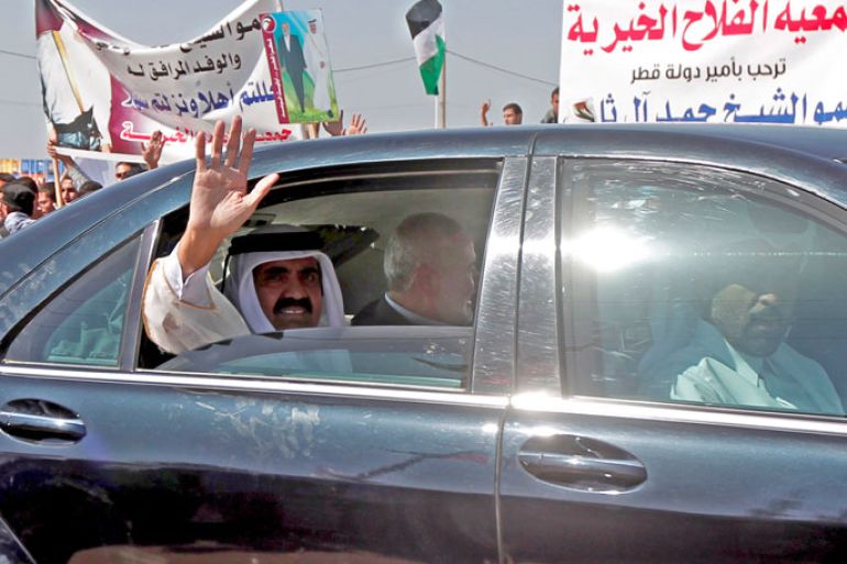 RAFAH, GAZA STRIP, - : Qatari Emir Sheikh Hamad bin Khalifa al-Thani waves to the crowds as he sits next to Gaza's Hamas prime minister Ismail Haniyeh during a welcome ceremony at the Rafah border crossing with Egypt on October 23, 2012 in the Gaza Strip. Sheikh Hamad bin Khalifa al-Thani arrived in the Gaza Strip in the first visit by a head of state since the Islamist Hamas movement took over in 2007. AFP PHOTO/MOHAMMED ABED