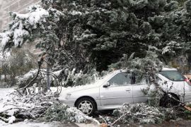 : A car sits under fallen tree branches following an overnight snow storm in Grenoble on October 28, 2012. AFP PHOTO / Jean Pierre Clatot